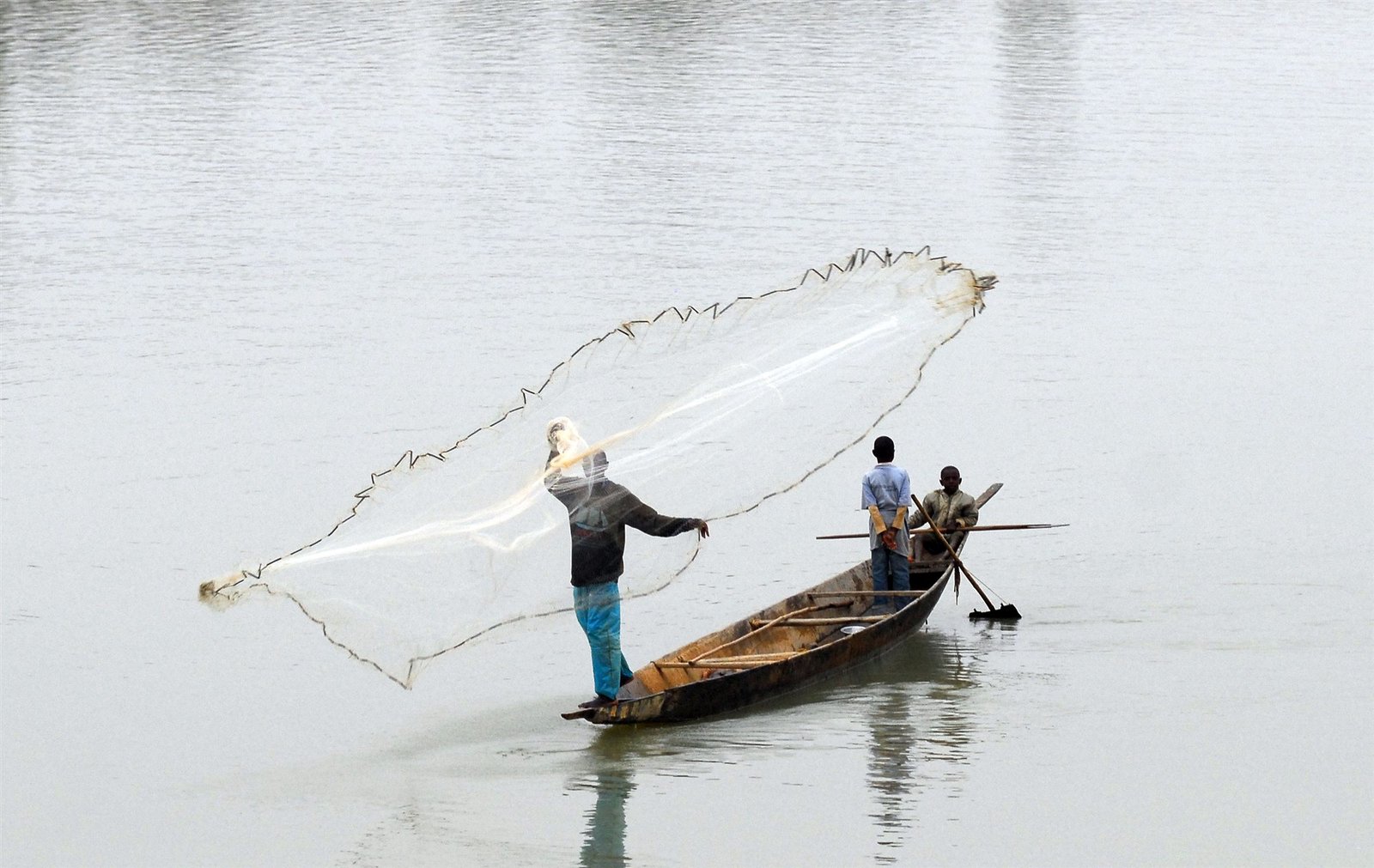 Pêcheurs à l’épervier : le filet se déploie depuis une pirogue — Stéphane Lhôte