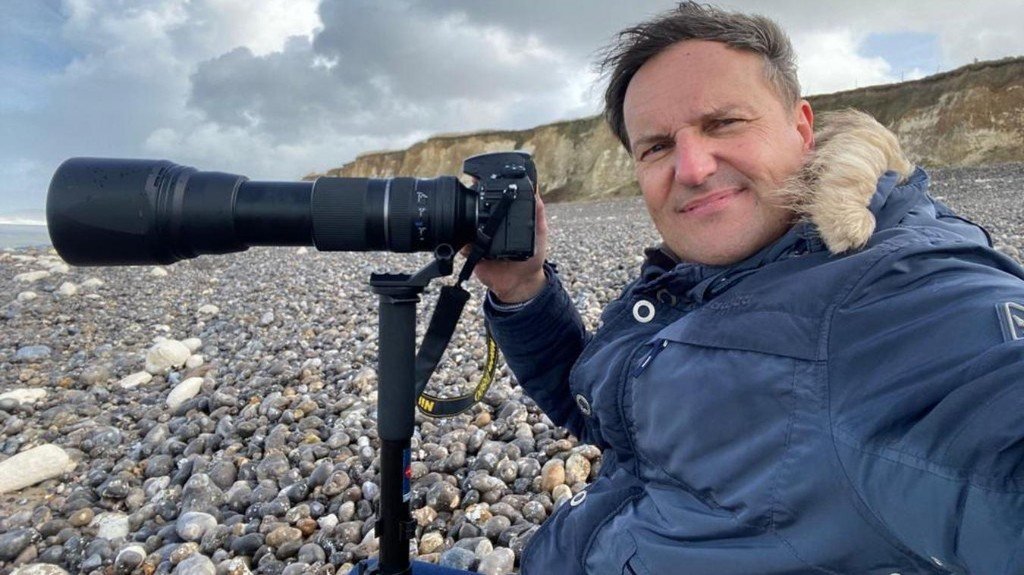 Stéphane Lhôte, photographe, sur une plage de galets en Normandie