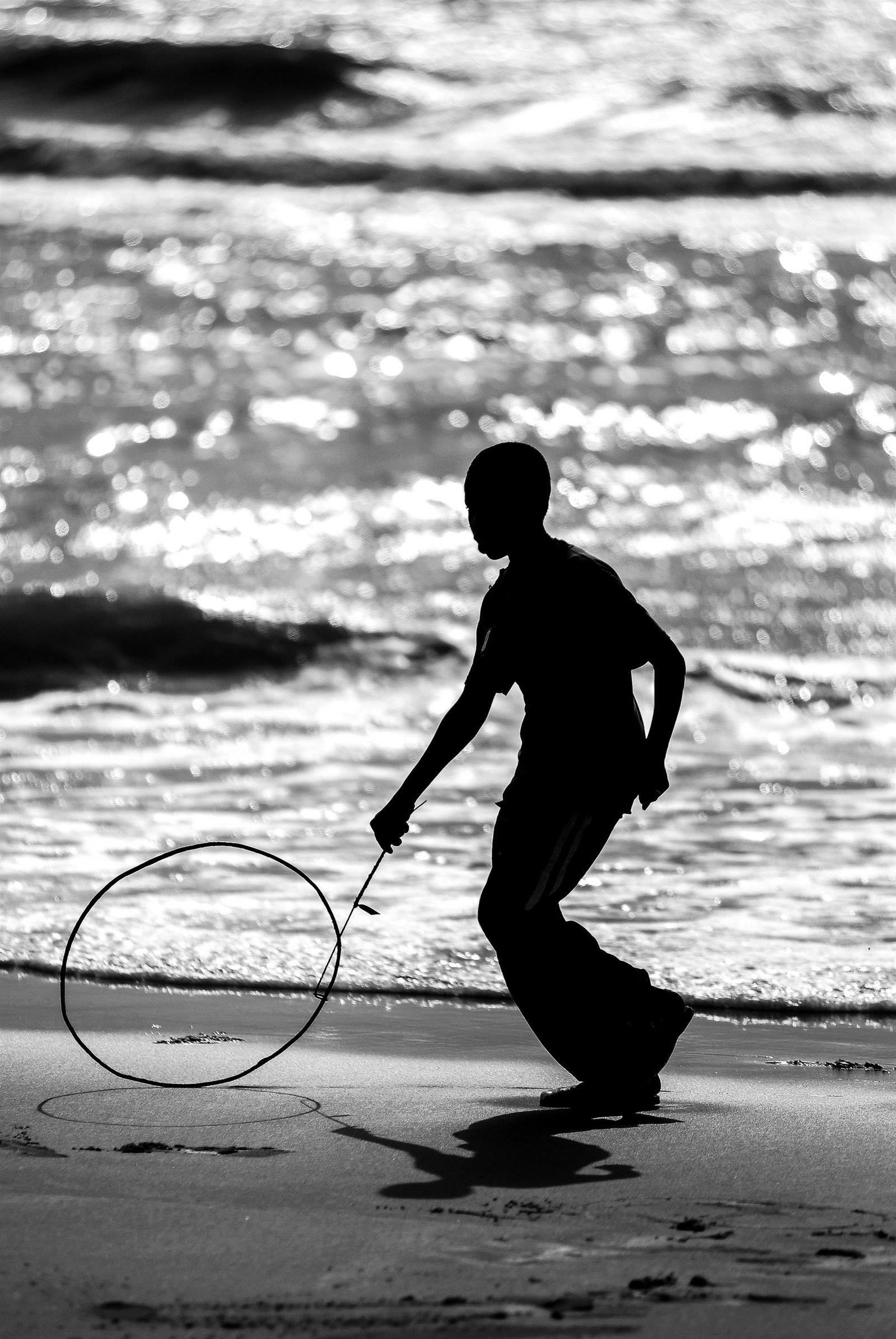 Enfant au cerceau sur la plage, silhouette contre-jour — Stéphane Lhôte